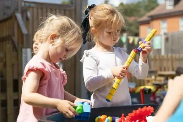 Children playing with toys outdoors at Monkey Puzzle Day Nursery Sunbury.